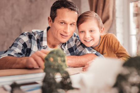 Lean on shoulder. Smiling handsome blue-eyed boy feeling extremely secure while leaning on his father shoulderの写真素材