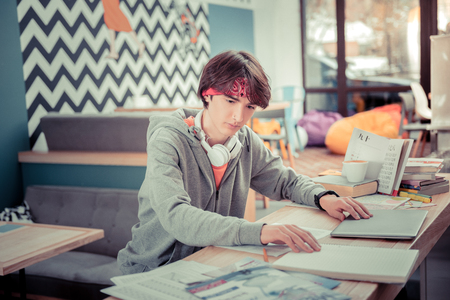 Books and gadgets. The student working on his paper using books and online resourcesの写真素材