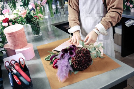 Conscious worker. Professional designer standing at his workplace and creating bouquetの写真素材