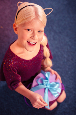 Joyful mood. Cute blonde keeping smile on her face and having birthday partyの写真素材