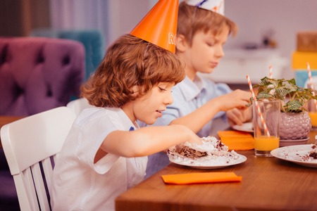 Kids cafe. Attentive teenager sitting in semi position while trying dessertの写真素材