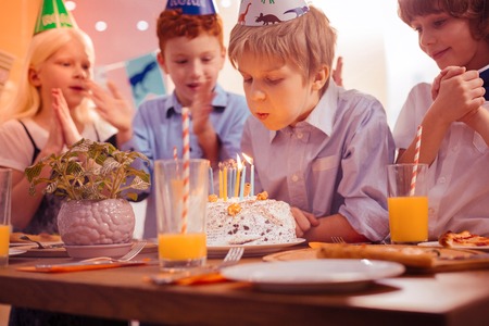 So concentrated. Positive delighted kids standing near their friend and clasping hands