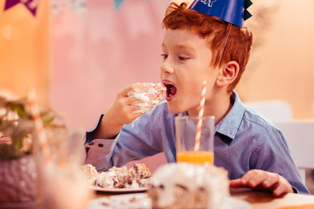 Open mouth. Emotional man child wearing paper hat and visiting kids cafeの写真素材