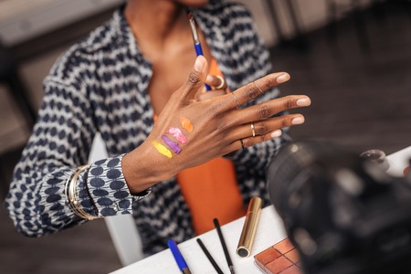 Beautiful dark-skinned african american woman with a gold bracelet putting new swatches on her handの写真素材