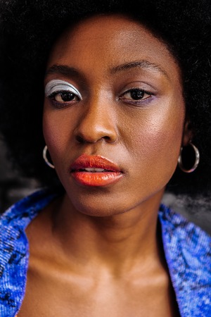 Thoughtful look. Cute african american model with coral lip gloss looking thoughtful while posing...