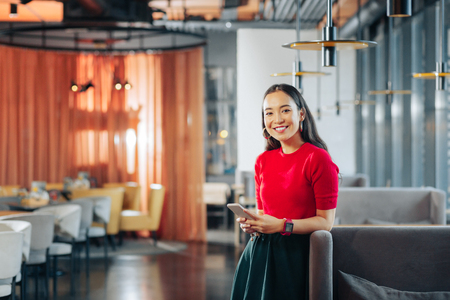 Cheerful woman. Cheerful dark-eyed fashionable woman standing in big spacious restaurantの写真素材