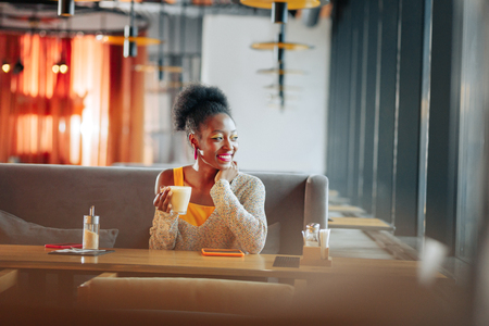 Enjoying time. Appealing stylish woman enjoying her time drinking coffee in her favorite restaurantの写真素材