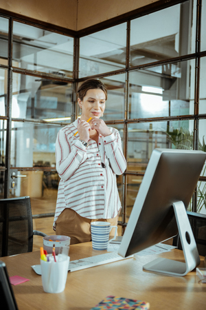 Pregnant businesswoman. Young pregnant businesswoman wearing stylish blouse working in modern officeの写真素材