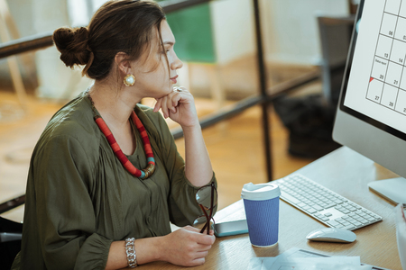 Drinking coffee. Dark-haired businesswoman working on computer and drinking coffeeの写真素材