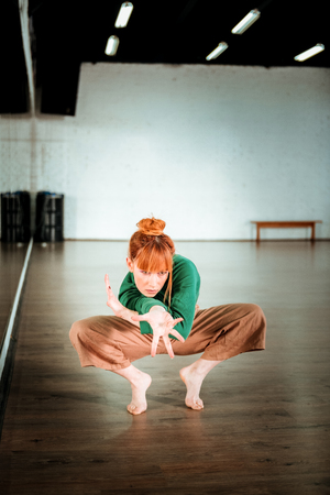 Workout. Cute red-haired yoga teacher wearing a green turtleneck looking focusedの写真素材