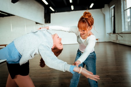 Back leaning. Pretty long-haired teenager wearing black shorts practicing leaning at the ballet schoolの写真素材