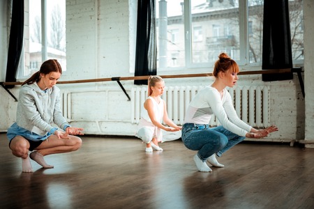 Inspiration. Red-haired dance teacher wearing blue jeans and her students looking inspired