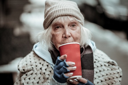 So hot. Sad poor woman standing with a cup of tea while drinking itの写真素材