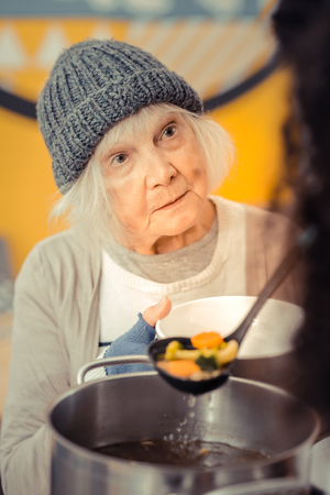 Hungry life. Sad cheerless woman asking for the soup while coming to the volunteer centerの写真素材