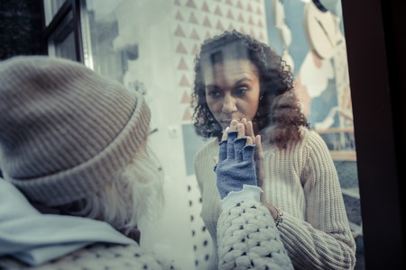 Come inside. Nice young woman opening the door of the cafeteria while asking the aged woman to come...