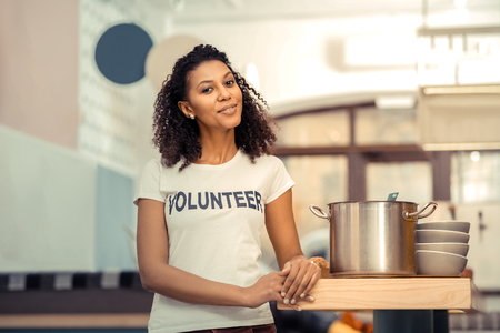 The soup is ready. Joyful afro American woman smiling while standing near the saucepanの写真素材