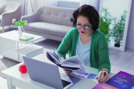 Professional numerologist. Nice good looking woman studying special literature while working as a numerologistの写真素材