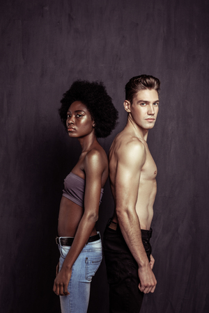 Interesting concept. Pleasant multinational couple standing together while being photographedの写真素材