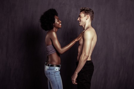 Tactile feelings. Positive afro American woman touching her boyfriend while smiling to himの写真素材