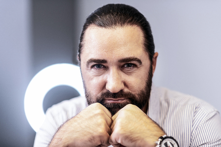 Serious man. Dark-haired bearded man wearing a striped shirt looking concentrated
