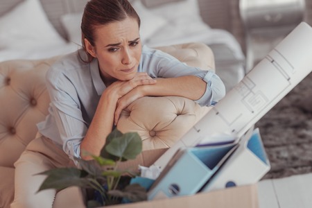 Feeling alone. Displeased young woman expressing sadness in her eyes while keeping her head on hands and looking awayの写真素材