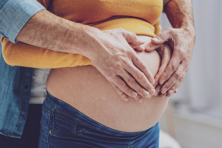 Feel his support. Young woman demonstrating her belly while expressing loveの写真素材