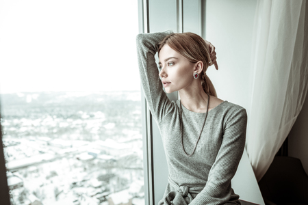 Elegant woman. Elegant fashionable blonde-haired woman looking into window enjoying the viewの写真素材