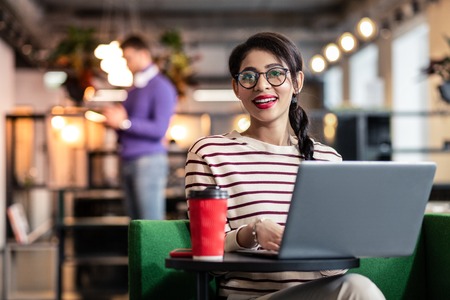 Modern technology. Charming girl wearing stylish glasses while posing on cameraの写真素材