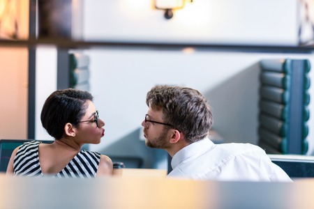 Sweet kiss. Cute girl turning head while going to kiss her colleagueの写真素材