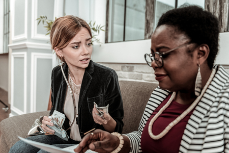 Payoff for fortune-telling. Young long-haired young woman wearing a black jacket giving money to the fortune-tellerの写真素材