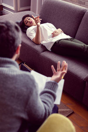 Young patient. Nice beautiful woman holding her finger up while speaking to her doctorの写真素材