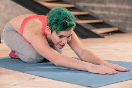 Attending fitness. Beautiful green-haired woman wearing pink top attending fitness center after work