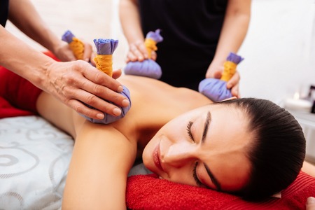 Extraordinary massage. Pleasant woman enjoying gentle treatment while masters stroking her naked body in SPA cabinetの写真素材