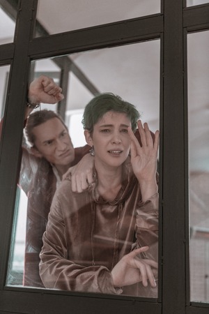 Living in danger. Young wife feeling helpless while living in danger having aggressive husbandの写真素材