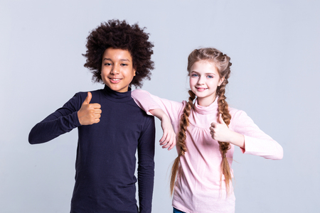 Standing near girl. Joyful cute kids working as models for professional photoshoot and showing their thumbnails on cameraの写真素材