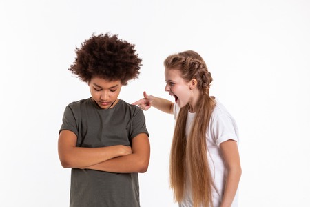 Aggressively screaming. Crazy expressive little girl touching her wilted dark-haired friend and...