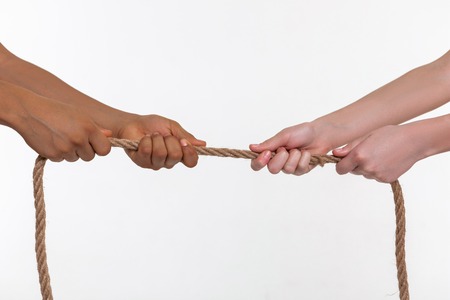 Bronzed hand. Little kids using all their forces while pulling thick rope from one side to another