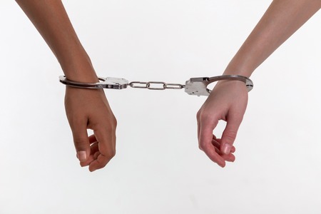 Involved children. Hands of little kids being closed in rough metal handcuffs during illegal action