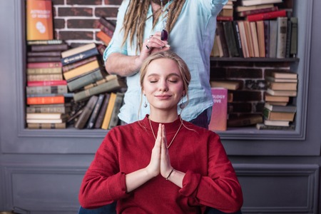 Absolutely calm. Delighted good looking woman smiling while closing her eyes
