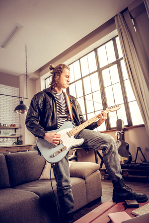 Much satisfaction. Curly talented musician with hair bun getting much satisfaction playing rock musicの写真素材