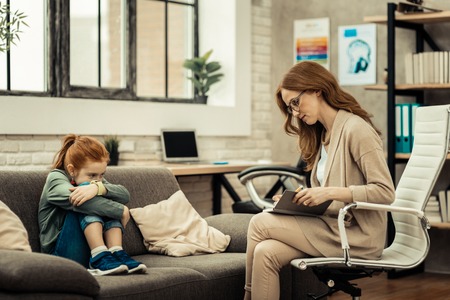 My patient. Serious smart woman reading her notes while having a session with her patientの写真素材