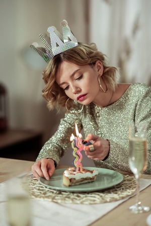 Candle on cake. Beautiful birthday woman wearing gold ring earrings burning the candle on cakeの写真素材