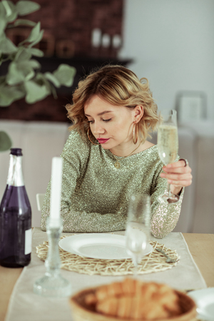 Croissants and champagne. Curly appealing woman sitting at the table with croissants and champagne aloneの写真素材