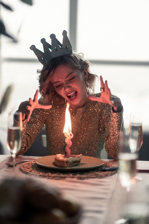 Hating everything. Blonde-haired young woman hating everything staying alone on her birthdayの写真素材