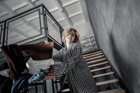 Throwing box. Sad and depressed woman wearing squared shirt throwing box with clothes awayの写真素材