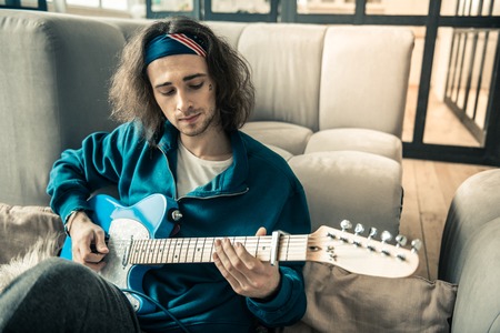 Professional instrument. Inspired young musician having tattoo on his face while learning new accords and compositionsの写真素材