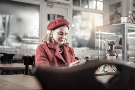 Pleasant smile. Beautiful woman expressing positivity while reading messageの写真素材