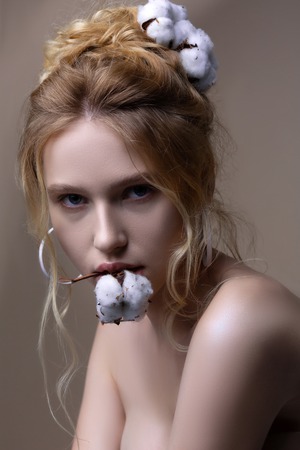 Model posing. Professional model posing with piece of cotton plant in her mouth and in hairの写真素材