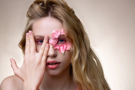 Young model. Young professional model with pink little petals on face showing nice posesの写真素材