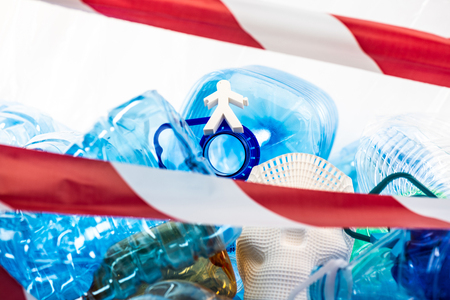 Chance for release. Abstract fake models of people lying between bunch of used plastic fenced with red lineの写真素材